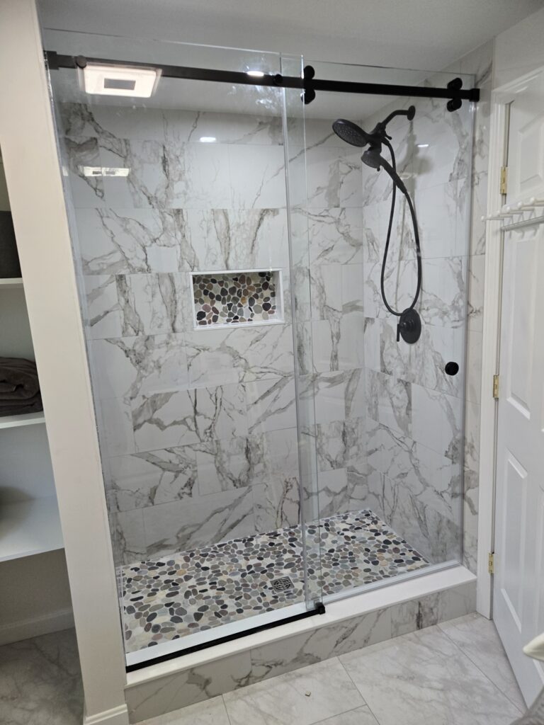 A marble shower with a frameless shower door